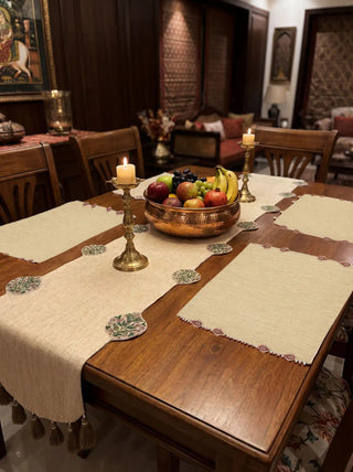A full festive dining tablescape set up with Gulnaz embroidered table mats, a matching linen runner, brass candlesticks, and a copper fruit bowl.
