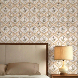 The Gulshan Indian design wallpaper in Sand styled behind a neutral upholstered bed with a warm lamp.
