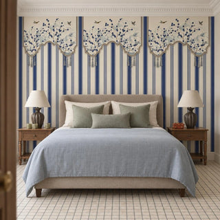 The Hana Stripes navy and ivory wallpaper installed on a feature wall in a bedroom behind an upholstered bed with sage cushions and a blue throw view-bedroom