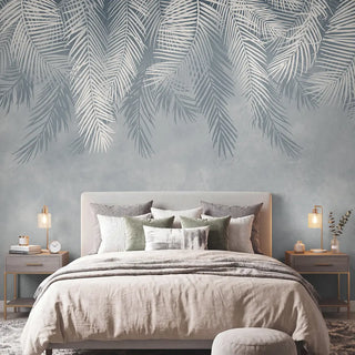 The Hanging Tropical Leaves botanical mural styled behind a modern upholstered bed in a serene, luxury bedroom.