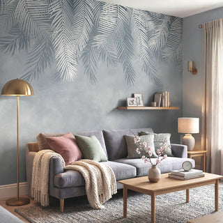A luxury living room featuring the Hanging Tropical Leaves mural in blue behind a grey sofa with pastel accents.