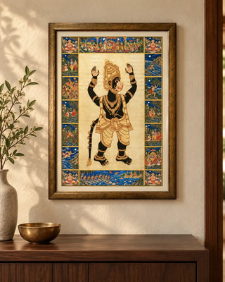 Hanuman Ansh framed wall art on a warm cream wall above a dark wooden console with a brass bowl and a stone vase of flowering sprigs.