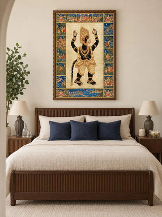 Hanuman Ansh wall art in a dark wooden frame above a fluted walnut bed with cream bedding, navy cushions and a pair of linen-shaded table lamps.