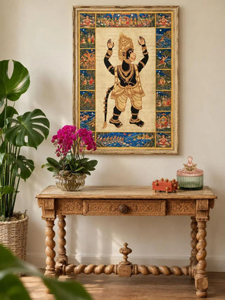 Hanuman Ansh wall art in a distressed gold wooden frame above a carved wooden console with twisted legs, a magenta orchid and a large monstera.