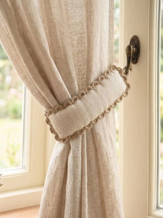 A detailed close-up view of the Hazel Verse scalloped tieback holding a translucent open-weave linen sheer drape next to a vintage window handle.
