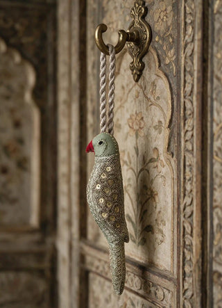 The Heer charm in Sage & Gold, view-cabinethandle hanging from a brass handle on a carved wooden cabinet.