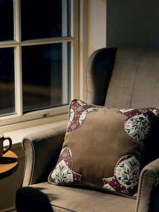 A Rustic Frame cushion placed on a dark-grey armchair near a window at night.