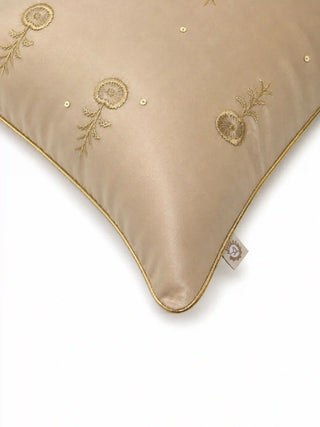 A high-resolution close-up of the gold silk-satin ground, hand-guided floral buta embroidery, and stitched gold sequins on the Hiranya cushion cover.