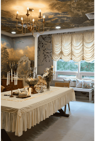 Decorative interior with a table set for a meal, candles, and elegant curtains.