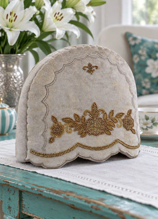 The Hoor tea cosy in Stone, view-livingroom beside white lilies and a striped teapot.