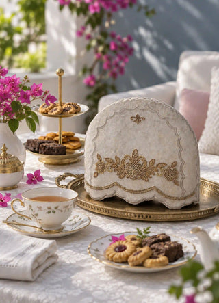 The Hoor tea cosy in Stone, view-terrace styled beside bougainvillea and a tiered cake stand.