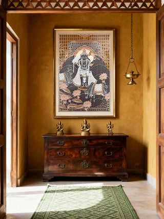 The Shyam Sundar hand embroidered wall art framed in a vintage-style yellow foyer above a wooden chest.