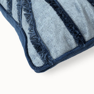 Close-up of the blue cushion corner showing the navy fringed wave stripe and blue piping.