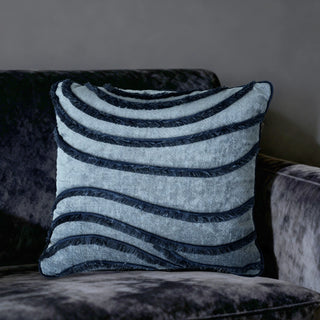 Single Indigo Wave Cushion displayed on a dark grey velvet chair for a moody contrast.