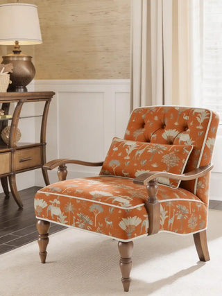 A luxury tufted armchair upholstered in Itihaas Red fabric featuring a hand-painted safari scene with elephants and giraffes.