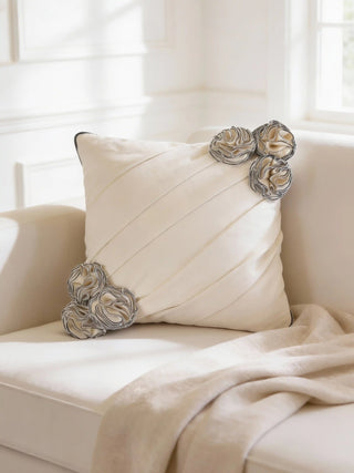 A luxury Ivory Gardenia cushion cover in cream featuring diagonal pleats and 3D fabric rosettes on a minimalist white sofa.