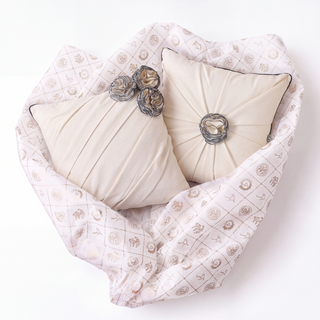 Overhead view of Ivory Gardenia draped pillows showing quilted ivory covers with celestial motifs, pleated cream fabric centers, and metallic rose embellishments.