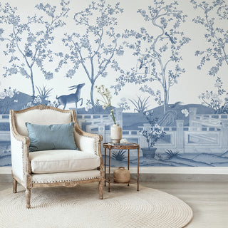 Jade Blossom blue Chinoiserie mural featuring an antelope and garden scene styled behind a classic white armchair. view-livingroom