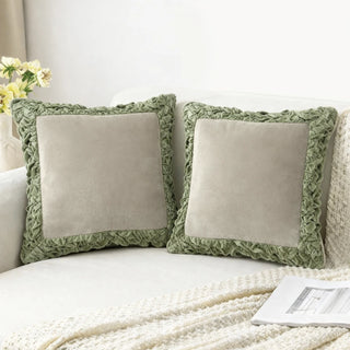 A pair of Jhalak ivory and green cushions styled on a cream-colored luxury sofa.