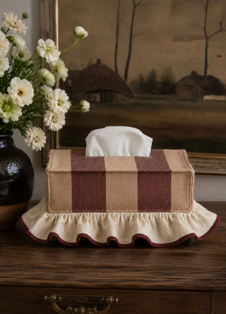 The Juliet tissue case in Wine & Camel, view-dresser beside a vintage landscape painting.