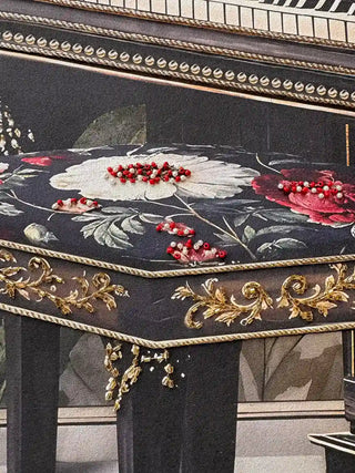 A detailed macro close-up of the Jungle Noir embroidered wall art showing red and pearl beads on the floral piano stool cushion.