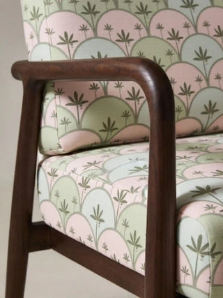 Close up of a dark wood armchair upholstered in Kannan fabric, highlighting the arched Art Deco palm design.