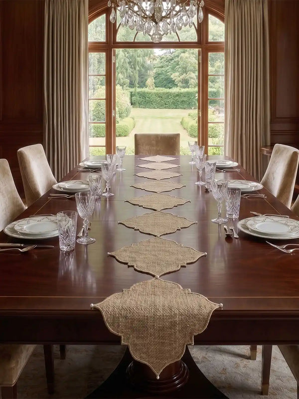 The Kasbah Pearl Jute Runner styled symmetrically down a long, polished mahogany wood table inside a luxury formal dining room.