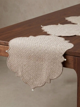 A macro detail shot showing the textured basket-weave pattern, corded border, and neat seed pearl anchor on the Kasbah Pearl runner.