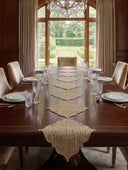 The Kasbah Pearl jute runner draped elegantly over the edge of a polished walnut wood dining table.