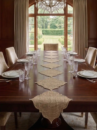 The Kasbah Pearl jute runner draped elegantly over the edge of a polished walnut wood dining table.