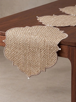 Side view of Kasbah Pearl Jute Table Runner draped over the edge of a polished wooden dining table.