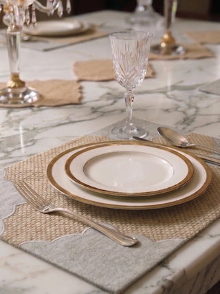Kasbah Pearl placemat styled on white marble with gold-rimmed china plates, silver cutlery, and crystal stemware.