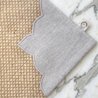 Close up of the woven jute texture and grey scalloped border with brand label on The Kasbah table mat