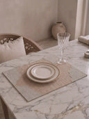 The Kasbah table mat with scalloped grey border styled with a gold-rimmed plate and crystal glass on a marble dining table