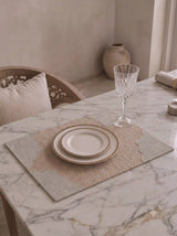 The Kasbah table mat with scalloped grey border styled with a gold-rimmed plate and crystal glass on a marble dining table