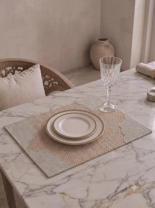The Kasbah table mat with scalloped grey border styled with a gold-rimmed plate and crystal glass on a marble dining table