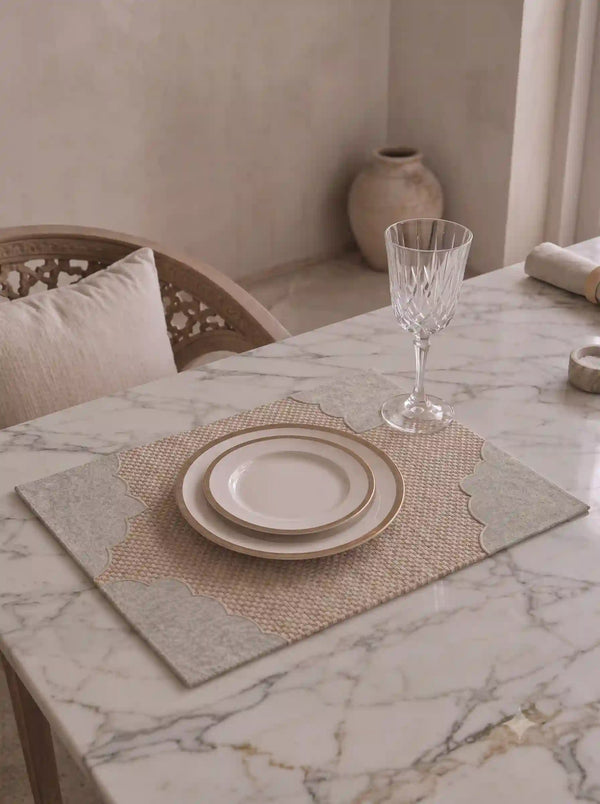 The Kasbah table mat with scalloped grey border styled with a gold-rimmed plate and crystal glass on a marble dining table