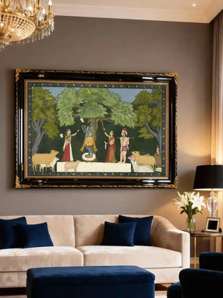 Krishna Leela with Gopis wall art in deep green, framed in black and gold above a cream velvet sofa with navy cushions and a crystal chandelier in a formal living room.