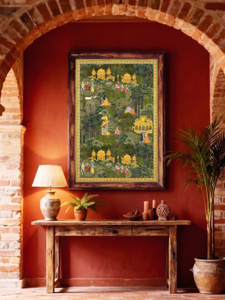 Krishna Leela pavilion and garden wall art in forest green and gold, framed in weathered wood on a deep red wall above a rustic console with a ceramic lamp and potted palm in a brick-arched entryway.