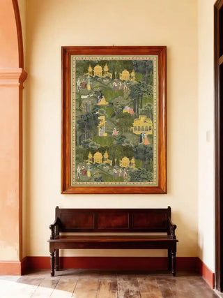 Krishna Leela wall art in forest green and gold, framed in polished rosewood above a dark wooden bench in a sunlit hallway with timber floors.