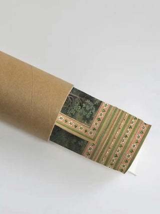 Krishna Leela wall art print in forest green and gold rolled in a kraft shipping tube, showing the white blossom and striped border detail.