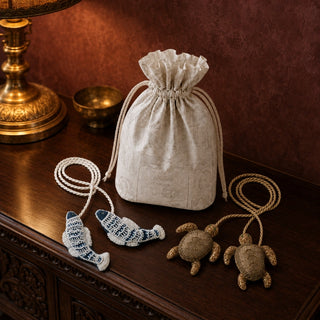 Kurma turtle and Matsya fish tiebacks styled beside a printed drawstring gift pouch on a carved wooden console