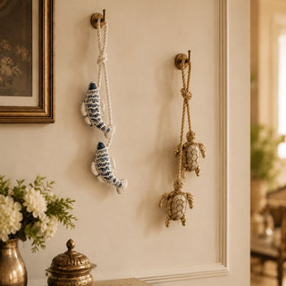 Kurma turtle and Matsya fish tiebacks hung decoratively from brass wall hooks beside a framed artwork