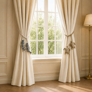 Kurma gold turtle and Matsya indigo fish tiebacks cinching cream curtains beside a sunlit window