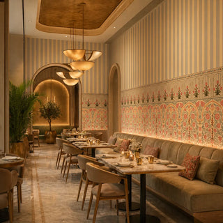 A luxury living room featuring the Kusum wallpaper with Mughal arches and vertical stripes behind a plush beige sofa, view-restaurants