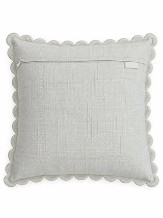 The back of the Leafora cushion cover: a plain pale woven panel with a zip along the upper edge, a small label tab and a scalloped border.