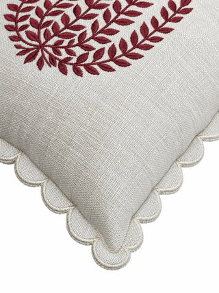 A close-up of the Leafora cushion cover showing satin-stitched burgundy leaves on a slubbed ivory weave, with a scalloped edge in a fine cream stitched outline.