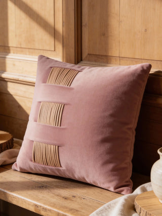 A luxury leather ridges cushion cover in rose velvet with tan leather accents resting on a rustic wooden bench.
