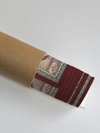 A close-up of the Aalishan artwork showing the crimson border and turquoise details as it is unrolled from a shipping tube.