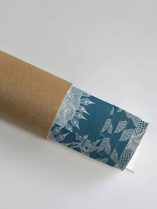 A close-up of the Geet Madhubani blue artwork showing the intricate white bird motifs as it is unrolled from a premium shipping tube.